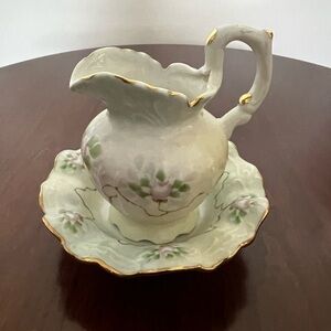 Small porcelain creamer and saucer floral design with gold trim.